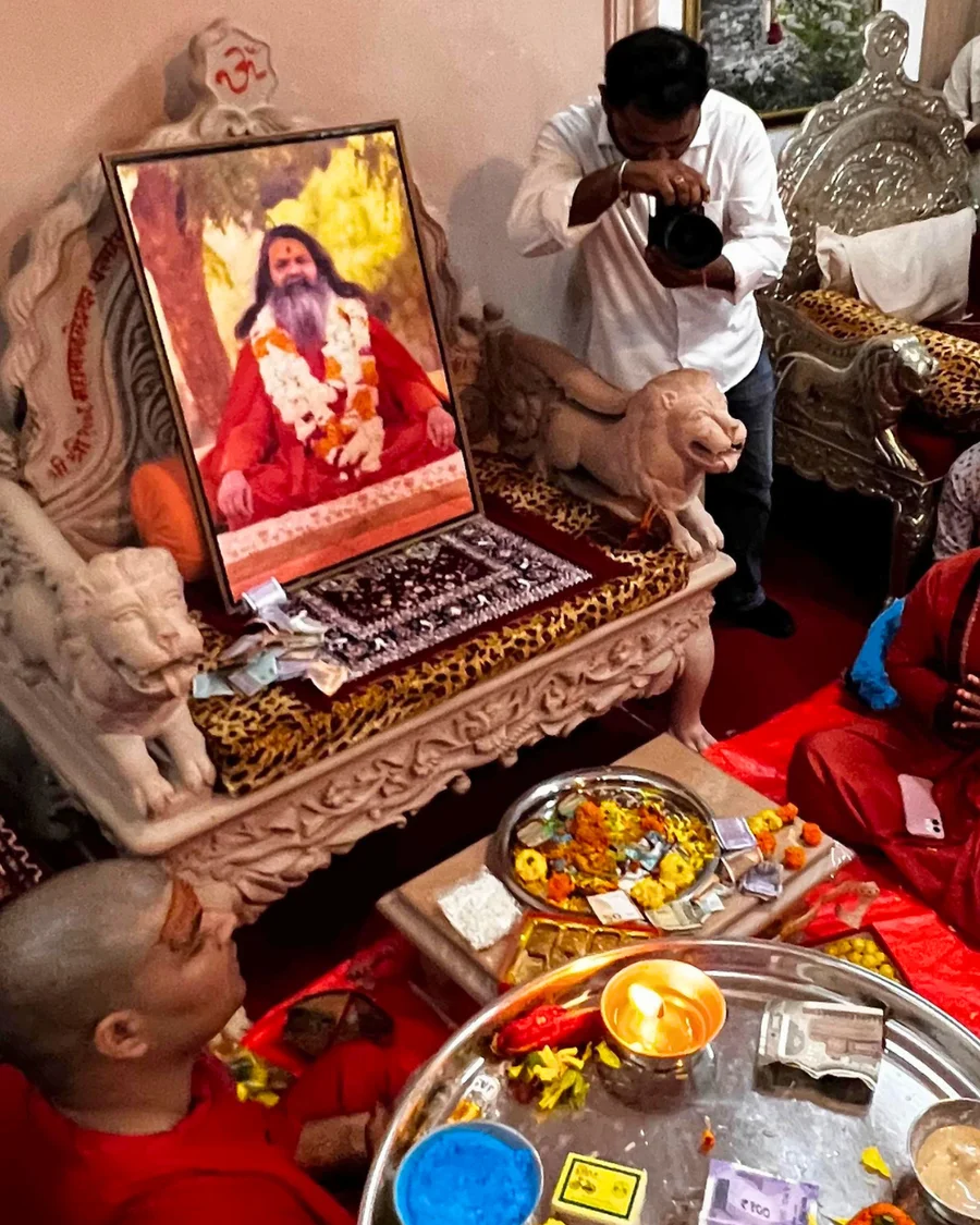 A traditional puja thali with flowers and lamps before the gadi of Gurudev.